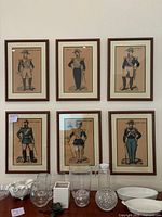Photo showing group view of all six framed lithographic prints depicting French soldiers in late 19th century uniforms with detailed ornate frames.