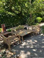 Group of two armchairs, one bench, and one coffee table outside on pavement