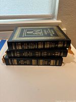Stack of three Oxford History books with black covers and gold embossed decoration showing titles on the spines: Greece and the Hellenistic World, The Roman World, Ancient Egypt.