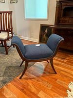 Photo showing side view of bench stool emphasizing curved wooden legs and upholstered seat.