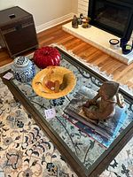 Glass top coffee table with Buddha sculpture, three pottery pieces, and books arranged on top.