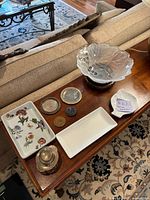 Overview of table contents showing multiple antique and collectible items including sterling silver, crystal dish, ceramic trays, and other decorative pieces.