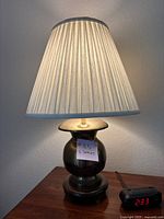 Lamps lit showing pleated cream-colored shades and bulbous brass bases on wooden platforms.