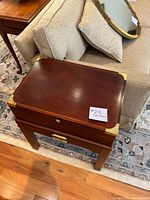 Front and top view of closed humidor table showing brown wood finish, brass corner protectors