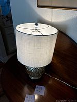 Full lamp view showing lamp shade and textured glass base on a corner cabinet.