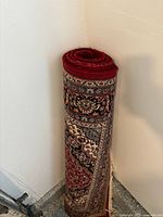 Rolled vintage rug positioned in a corner showing the intricate pattern and color scheme.