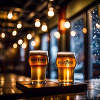 Two glasses filled with craft beer on a wooden surface inside the brewery's taproom, showing the Overflow Brewing logo on the glasses and warm ambient lighting.