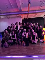 Group of women posing in mirrored dance studio under colored lighting