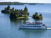 Excursion boat cruising past small forested islands