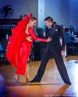 Couple dancing ballroom style in formal attire, showcasing elegant dance technique and style.