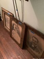 Three framed portraits leaning against wall