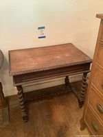 Full view of wooden table against wall showing carved apron and twist legs