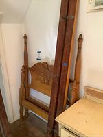 Bed frame components leaning against wall showing carved eagle headboard and rails