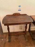 Front view of wooden writing desk showing drawer, turned legs and backboard
