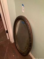 Full view of oval mirror leaning against wall