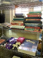 Full shelf with books, stationery, cat shakers and sealed board game