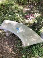 Full view of curved concrete bench in garden setting