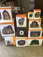 Stacked view of ten boxed Department 56 Snow Village Halloween pieces