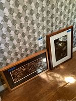Both framed prints leaning against wall