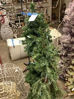 Two green artificial Christmas trees, one on stand, with lights