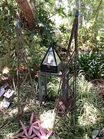 Two metal obelisk supports flanking black metal/glass terrarium on stand