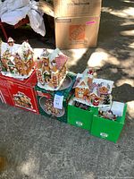Three gingerbread houses atop original boxes and two additional green boxes