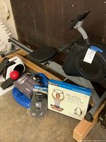 Rowing machine, compact elliptical, Pilates kit, balance cushion, massage ball and boxed accessory displayed together