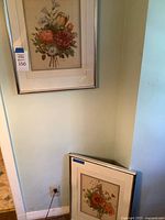 Two framed floral prints, one hung, one resting on floor