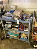 Full view of grey three-tier cart with assorted art supplies, puzzles, games