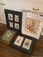 All four framed prints leaning against cabinet