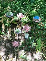 Group of multicolor ceramic flower stakes installed in garden bed