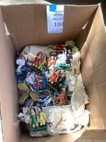 Top view of open box showing assorted painted figurines packed in paper