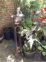 Full view of metal sculpture on stand with planters nearby