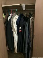 Closet view showing multiple uniforms, blazers and shirts on hangers