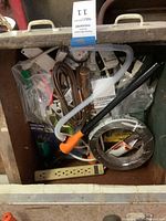Full view of box showing assorted tools, cords and power strip