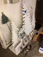 White wooden tree and reindeer silhouettes with light strand coiled at base