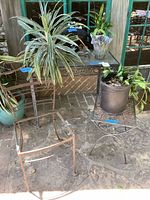 Overall lot showing chair frame, glass table with plant and statue, plant stand with potted plant