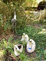 Crane statue, two swans and basket planter in garden setting