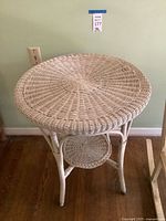 Full view of white wicker round table showing top and lower shelf