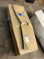 Closed cardboard box containing tree, secured with blue tie