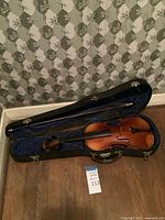 Violin in open blue-lined case with bow and rosin visible