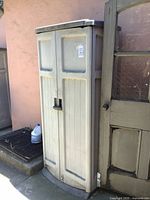 Full view of Suncast resin cabinet standing outside against wall