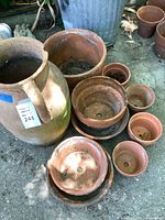 Group shot of all terracotta planters, jar, saucers and pots on ground