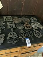 Overview of about 15-20 cast iron trivets on tabletop