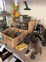 Overview of lot with microscope, binoculars, bulbs, eagles, box of parts, plastic fruit décor
