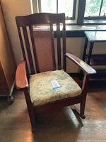 Full view of rocking chair showing wood frame, cane back, floral cushion