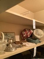 Shelf with assorted silver, glass and hat items