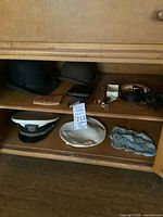 Cabinet shelf with hats, leather case, belt and accessory