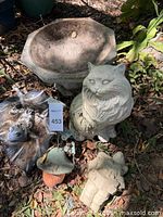 Group view of concrete bowl, cat statue, painted frog, mushroom, gnome, mosaic frog