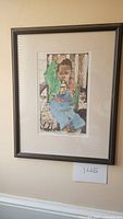 Photo of the framed artwork 'Big Babe' depicting a child in colorful clothing seated on wood background.